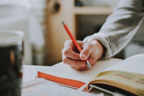 Hand holding a pen writing in a notebook