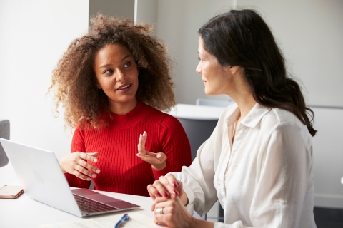 Two people at work talking in front of a laptop